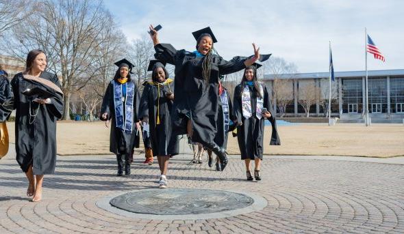 A student jumps in the air while walking across the ODU seal.